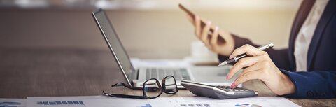 Rechnungserklärung online Ein Bürotisch mit Computer, Taschenrechner und Brille