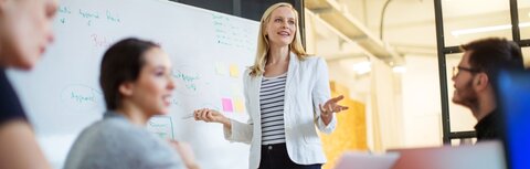 Strom Abgaben und Umlagen Eine Frau hält einen Vortrag vor einem Flipchart.