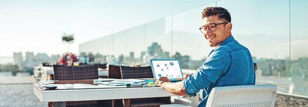 EWE business Strom fix Ein Mann auf einer Dachterrasse an einem Laptop