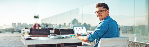 EWE business Strom fix Ein Mann auf einer Dachterrasse an einem Laptop