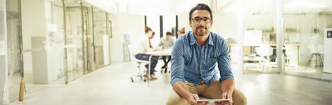 EWE business Strom flex Ein Mann auf einem Bürodrehstuhl in einem Büro