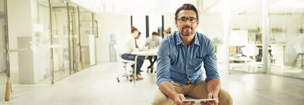 EWE business Strom flex Ein Mann auf einem Bürodrehstuhl in einem Büro
