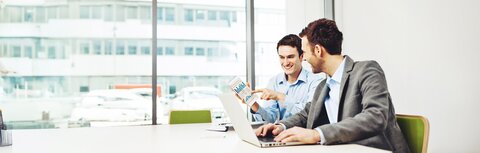 EWE business Strom logic Zwei Männer an einem Arbeitsplatz mit einem Laptop, die ein Diagramm ansehen