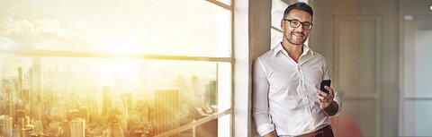 EWE business Wärme Ein Mann im weißen Hemd in einem Bürohochhaus, in das die Sonne scheint