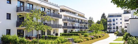 EWE business Fernwärme Weiße Mehrfamilienhäuser mit begrünten Wegen