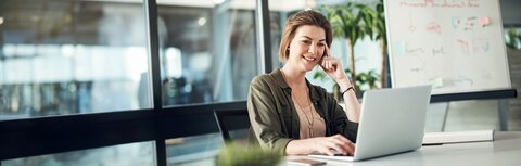 EWE business Online Seminar Eine Frau am Schreibtisch, die interessiert auf Ihren Arbeitsrechner guckt