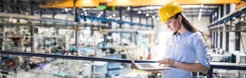 EWE Leased Line Frau mit Helm in Fabrikhalle schaut auf Laptop