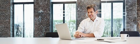 EWE Multi Connect Mann im weißen Hemd am Laptop