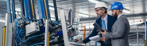 Digitale Vernetzung mit ENX von EWE Zwei Männer mit Helmen in Produktionshalle