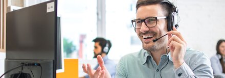 Telefonie von EWE Freundlicher Mann mit Headset vor einem Bildschirm