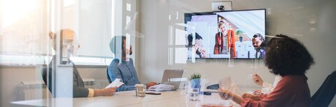 SIP von EWE Mehrerer Menschen im Konferenzraum schauen auf einen Bildschirm während einer Videokonferenz