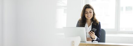 EWE Endpoint Protection Frau mit Handy in der Hand vor dem Laptop