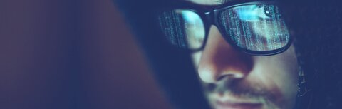 IT-Security Stilisierter Hacker blickt in die Kamera