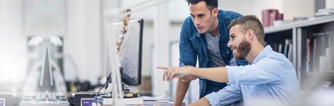Phishing-Check von EWE Ein Mann zeigt einem Kollegen etwas am Computer-Bildschirm