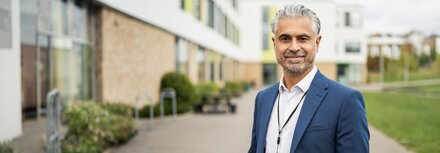 Branchenlösungen mit EWE business Ein Mann mit blauem Sakko steht neben einem Gebäude