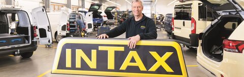EWE business Referenz INTAX Mann vor Firmenschild "INTAX"