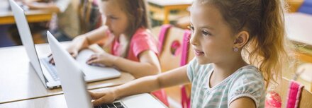 Förderung für die digitale Schule Kinder in einer Klasse vor Computern