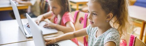 Förderung für die digitale Schule Kinder in einer Klasse vor Computern