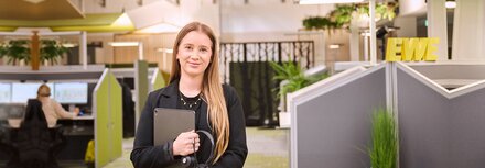 Service für EWE business Kunden Eine freundliche Service-Mitarbeiterin im EWE-Callcenter mit schwarzem Blazer und einem Tablet im Arm sowie Siegel der Wirtschaftswoche und WELT