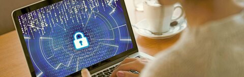 Daten-Backups Eine Frau versucht, ein Notebook zu entsperren, auf dem Code zu erkennen ist, im Hintergrund eine Kaffeetasse