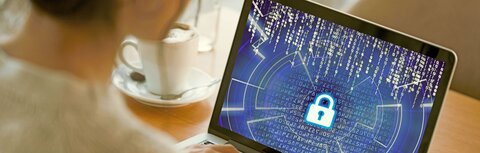 Interview mit ZAC-Experte Puschin zu Cyberkriminalität Eine Frau sitzt am Laptop und schaut auf den Bildschirm. Auf dem Bildschirm sind kryptische Zahlenkombinationen zu sehen und ein großes Schloss in der Mitte.