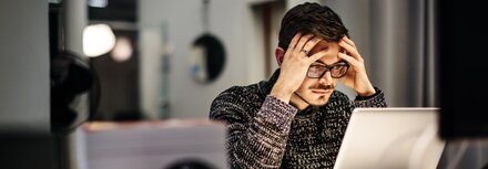 IT-Basisschutz Ein Mann sitzt im Büro vor einem Laptop und grübelt über einen erfolgreichen Cyberangriff auf seinen Arbeitgeber nach.