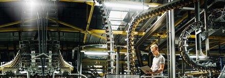 Licht-Modernisierung mit EWE business Ingenieur mit Laptop zwischen gut ausgeleuchteten Maschinen