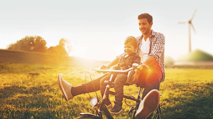 Mann und Junge fahren Fahrrad im Sonnenschein