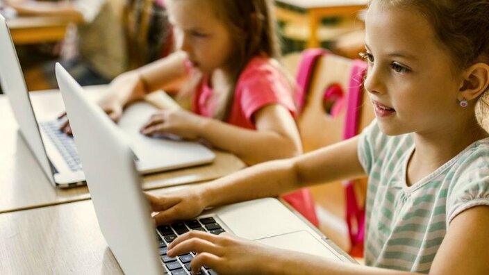 Mädchen in einem Klassenzimmer arbeiten an MacBooks