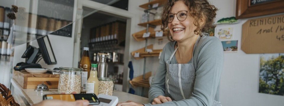 Ein Frau in einem kleinen Laden bedient einen Kunden