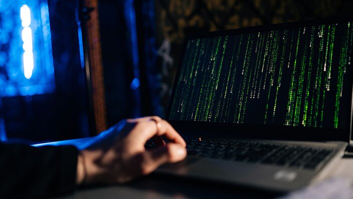 Person beobachtet DDoS-Angriff auf Laptop-Bildschirm