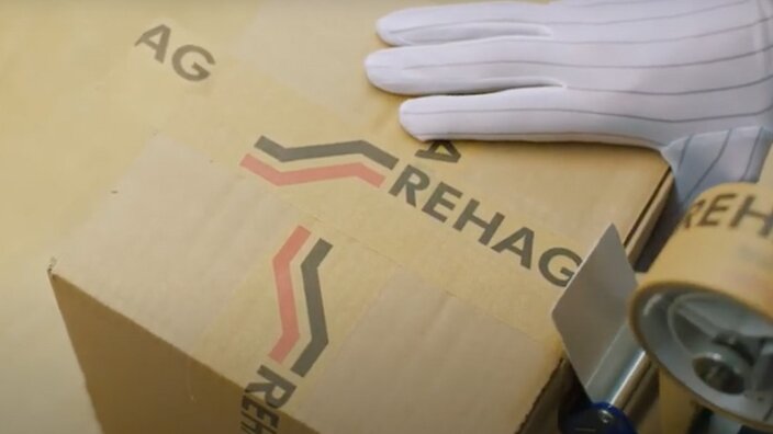 Ein Paket von REHAG Elektronik, das gerade per Klebeband sauber verschlossen wird