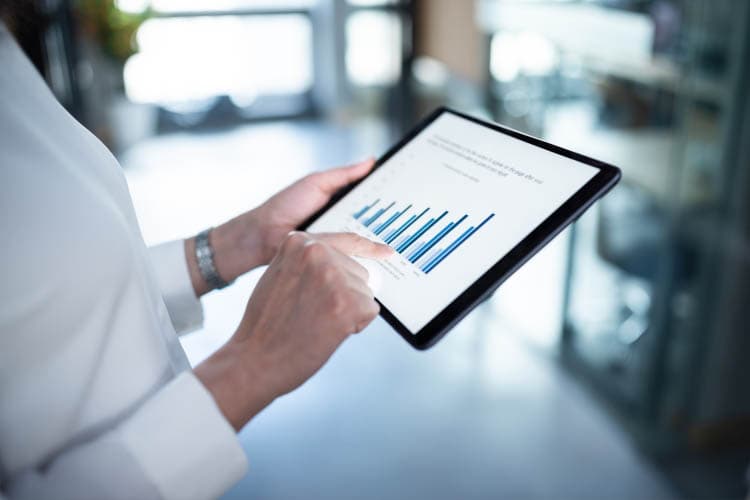 Eine Frau sieht es etwas auf einem Tablet an, auf dem ein Diagramm zu sehen ist.