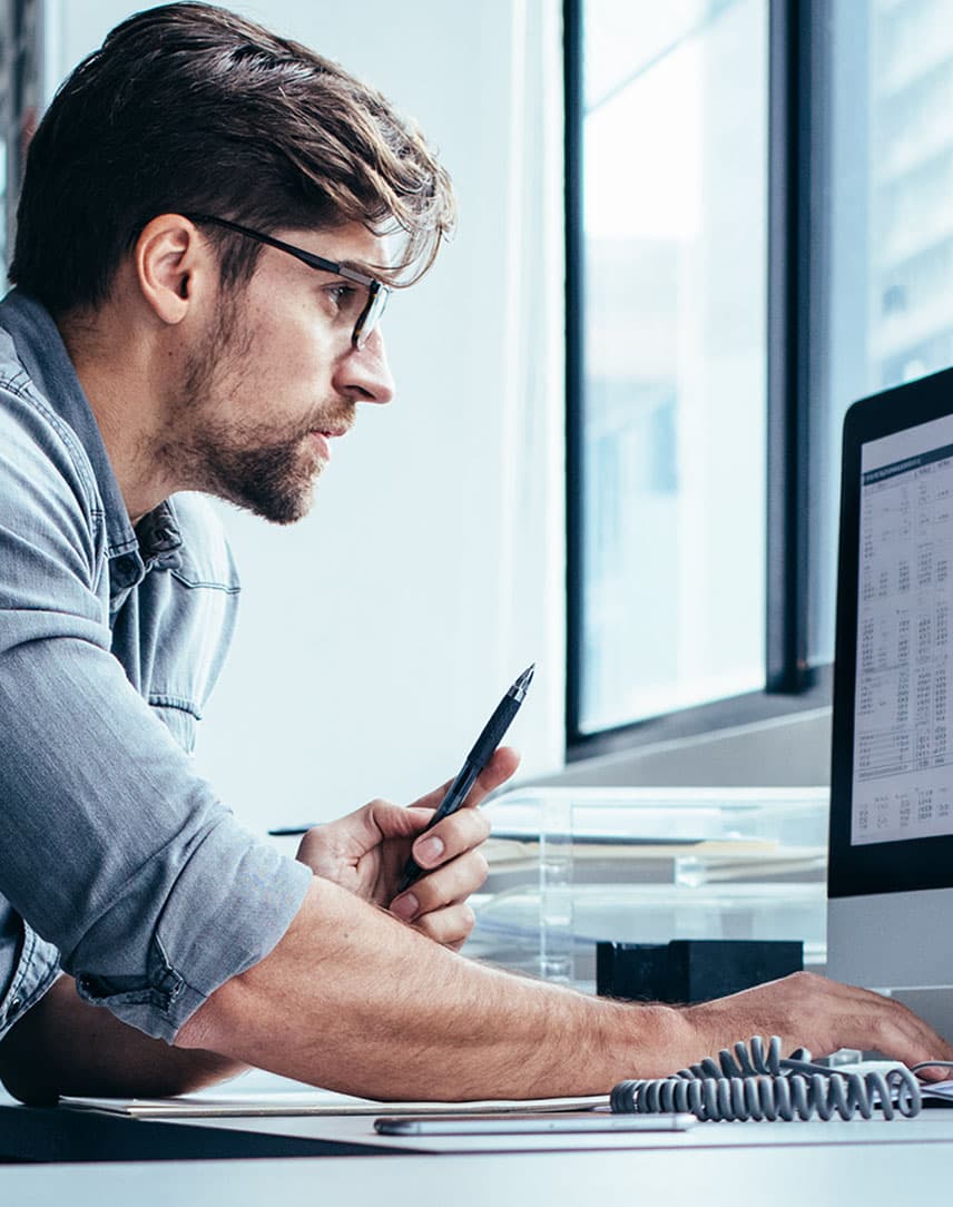 Ein Mann sitzt in seinem Büro vor einem Notebook und analysiert Daten
