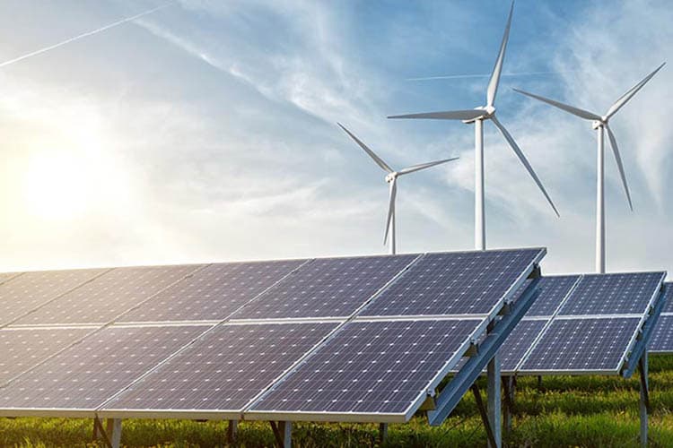 Ein Freiflächen-PV-Anlage, im Hintergrund Windräder