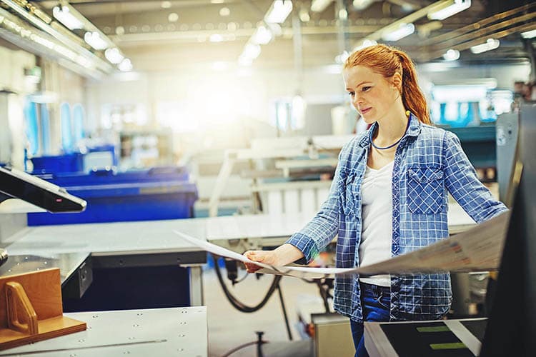 Eine junge Frau, die einen Proof in einer Druckerei prüft