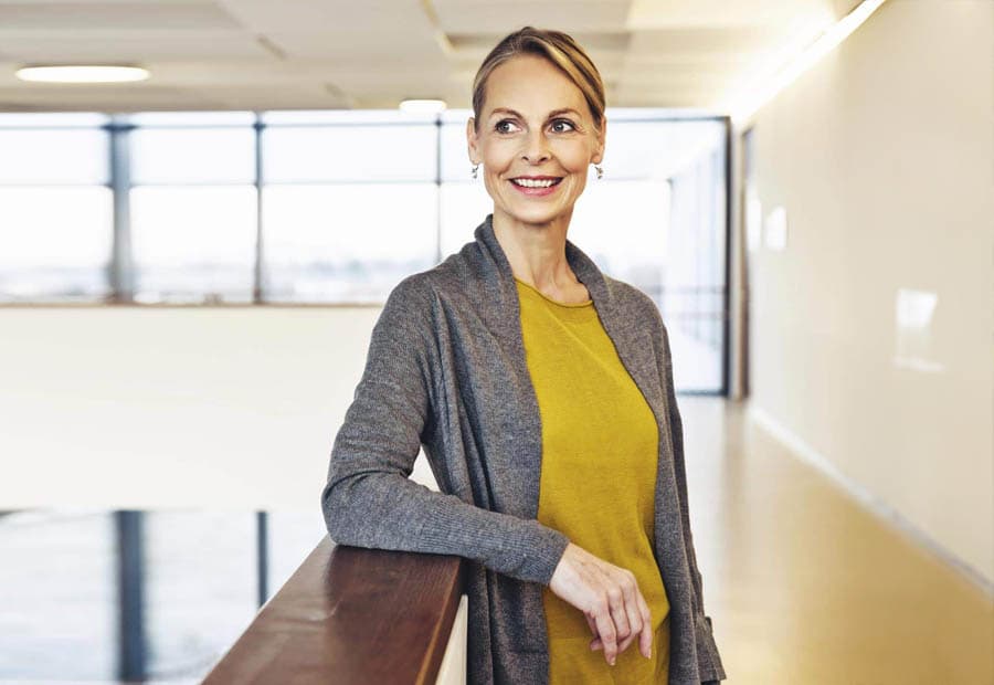 Eine lächelnde Geschäftsfrau, die an einem Geländer in einem Gebäude lehnt