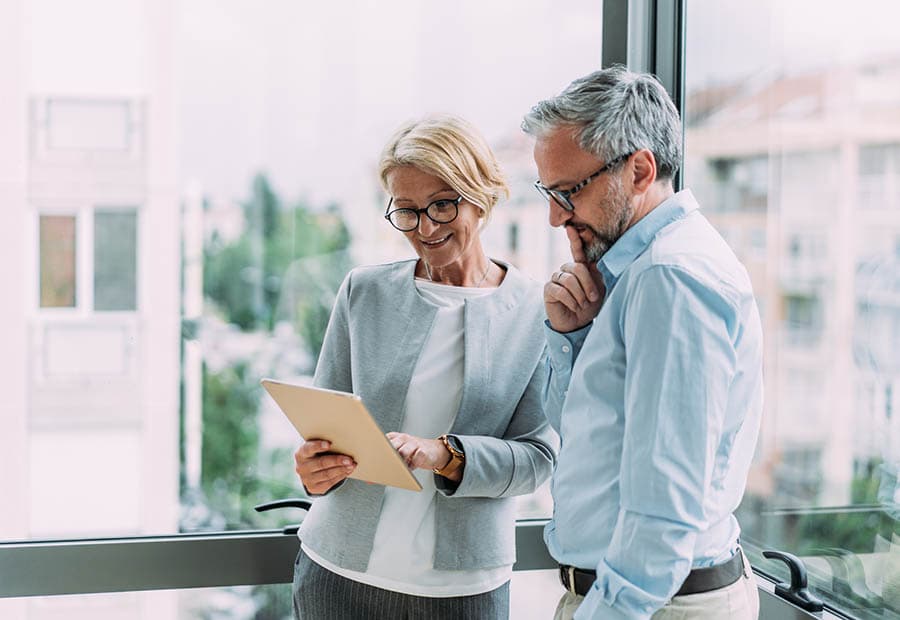 Ein grauhaariger Mann guckt sich etwas an, dass eine Frau ihm zeigt.