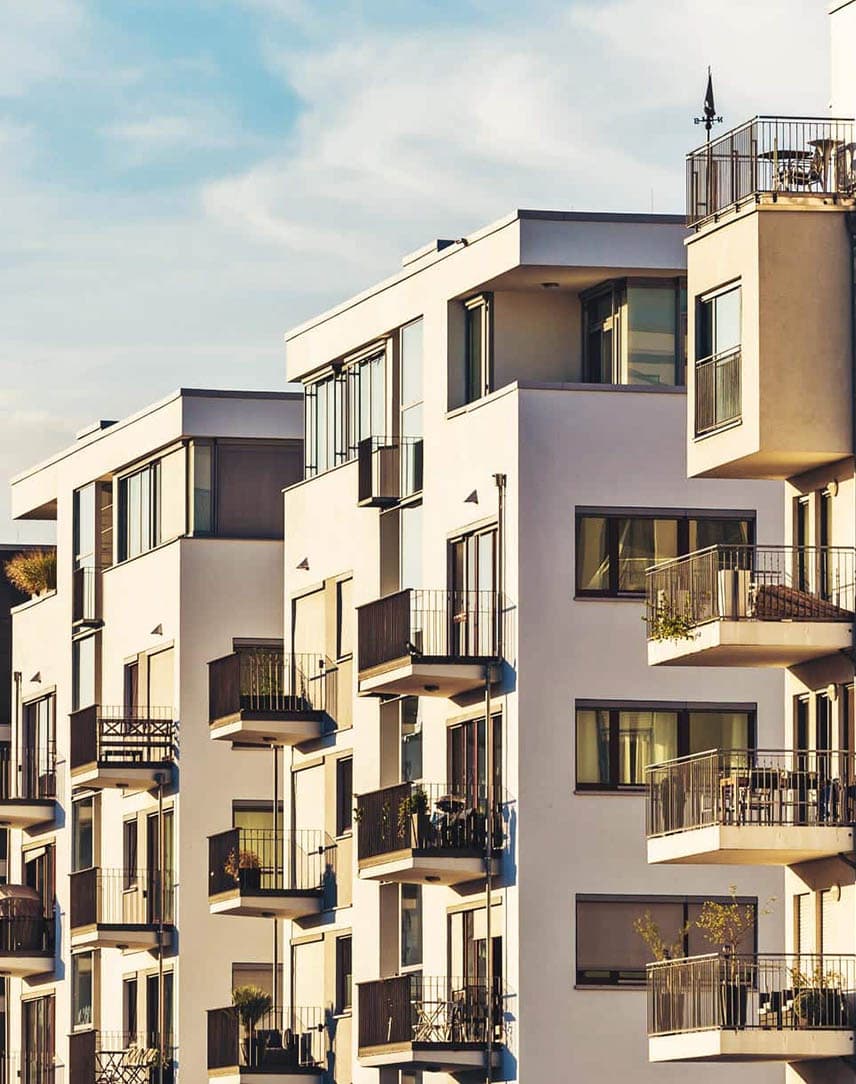Ein Häuserwand moderner Wohnblocks, dahinter blauer Himmel mit einigen Wolken