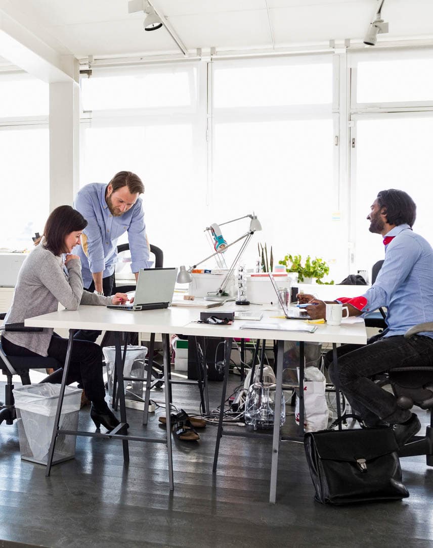 Mitarbeitende in einem Büro mit Computern und Bildschirmen an Schreibtischen