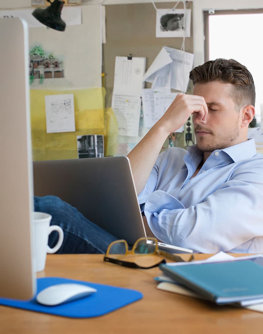 Ein Mann sitzt am Schreibtisch vor einem Monitor in einem Büro ärgert sich über einen erfolgreichen Hackerangriff auf sein Unternehmen