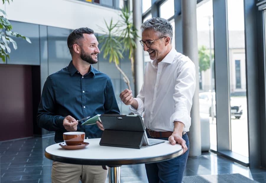 Zwei Männer unterhalten sich an einem Stehtisch in einem Unternehmen.
