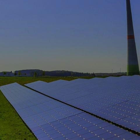 Photovoltaik mit EWE business PV-Module und Windräder auf einer grünen Wiese
