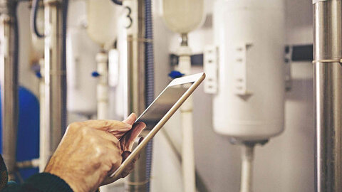 EWE business Wärme für die Pflege: Service Eine Person, die auf einem Tablet etwas an einer Heizung prüft