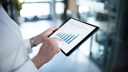 Analyse von Einsparpotenzialen Eine Frau guckt eine Grafik auf einem Tablet an.