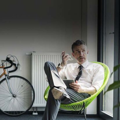 Mobilfunk Ein Mann in einem Sessel, der mit dem Handy telefoniert