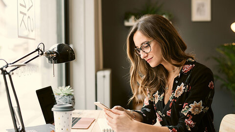 VPN mit Managed Firewall von EWE Frau im Büro schaut auf ihr Handy