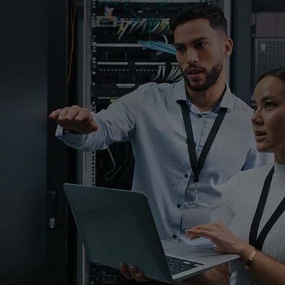 EWE Cyber-Security-Scan Abgedunkeltes Bild: Mann und Frau mit Laptop in der Hand im Serverraum