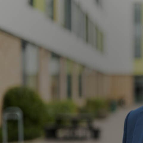 Branchenlösungen mit EWE business Ein Mann mit blauem Sakko steht neben einem Gebäude