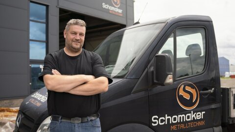 Mann vor Firmenwagen mit Logo Firma Schomaker EWE business Referenz Schomaker